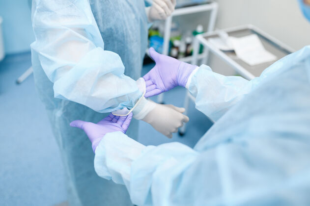 擦洗女外科医生和助理在手术室戴上手套 准备手术专业知识灯诊所