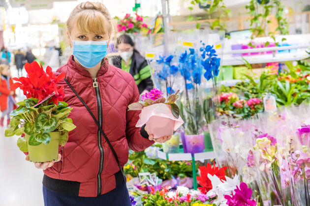 室内植物一个女人在花店的花盆里挑选一朵花温室女人面具