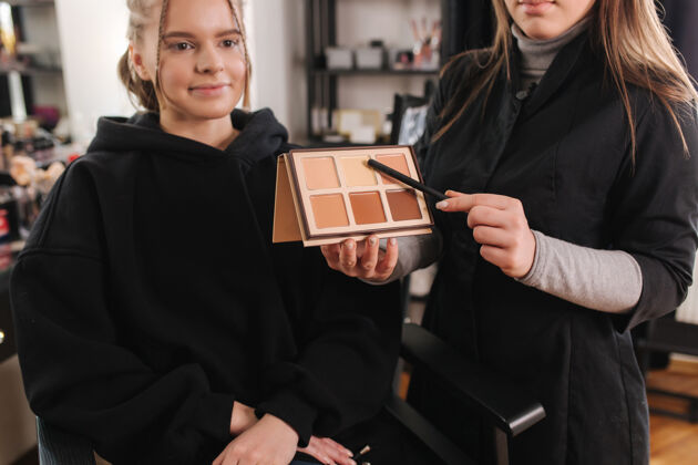 影响者女化妆师秀用调色板的颜色将使用化妆品艺术家与模特在工作室工作职业摄影棚拍摄在线