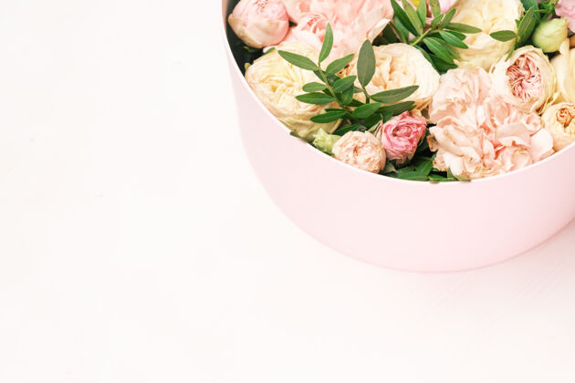 装饰一个时尚和精致的插花在一个帽子圆盒上的粉红色背景与复制空间鲜花节日婚礼