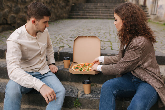 快一对夫妇在户外从盒子里拿比萨饼片朋友健康街道