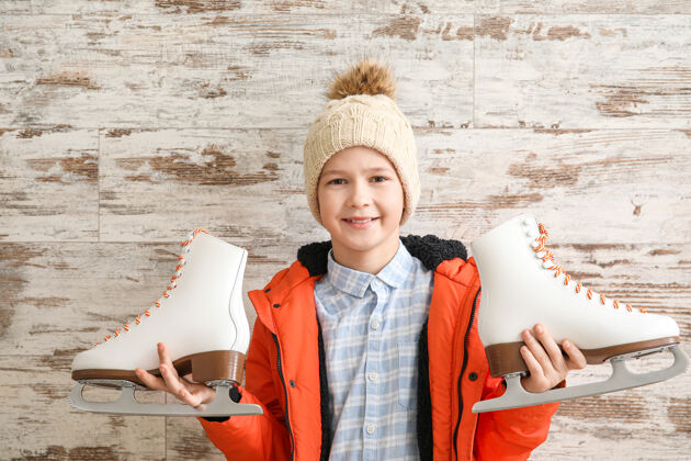 霜冻可爱的小男孩用冰鞋抵着木头休闲鞋活动