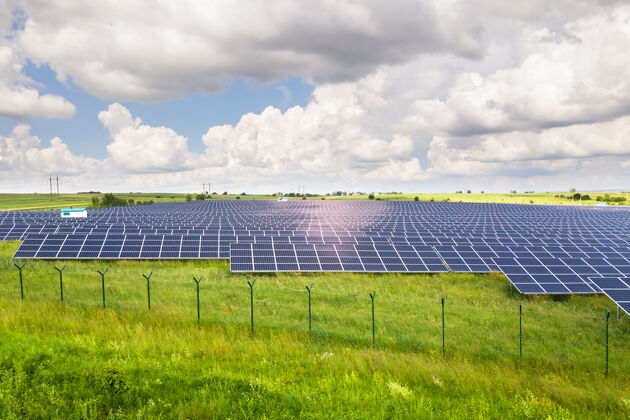地面周围有防护铁丝网的绿地上的太阳能发电厂鸟瞰图it.电气生产清洁生态能源的面板视图领土环境