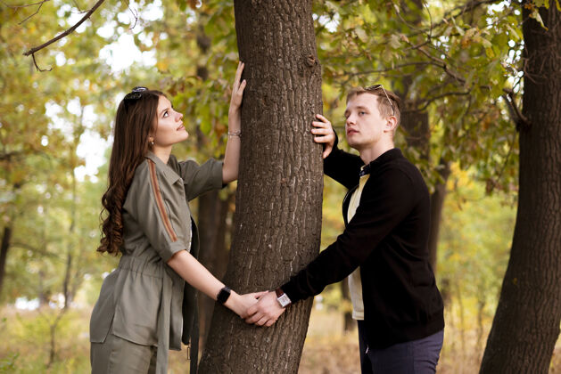 拥抱一对年轻的夫妇在森林里砍树 人们与自然观念联系在一起自然棕榈外面