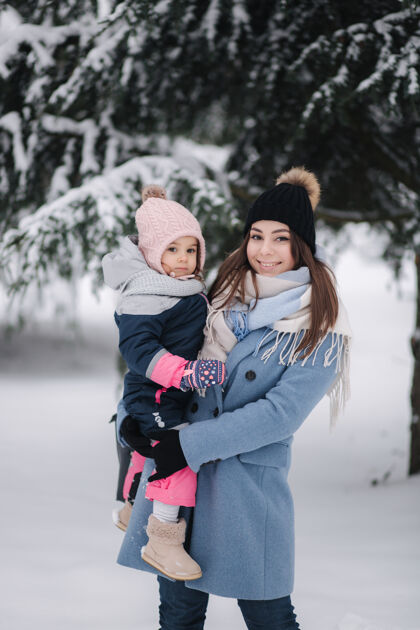 休闲美丽的年轻妈妈和她可爱的女儿在冬季公园运动父母享受