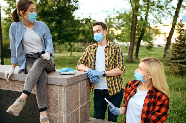 2019ncov戴着面具和手套的年轻朋友们在公园里悠闲地玩耍 隔离女性人在流行期间行走 保健和保护 流行的生活方式呼吸系统穿着散步
