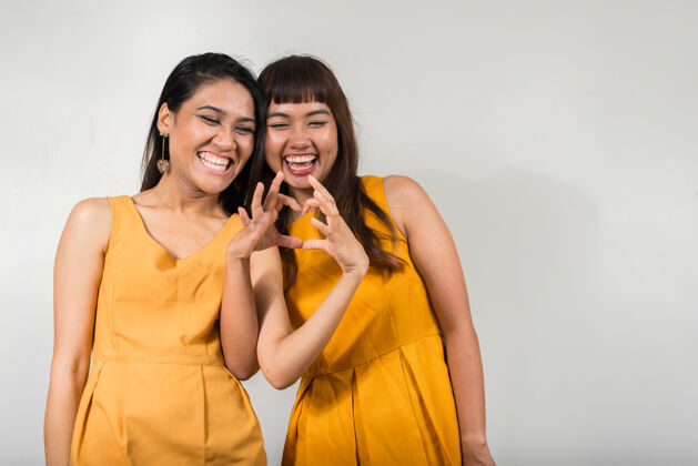 心两个年轻的亚洲女人一起对抗白色空间手夫妇朋友