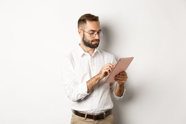 Male商人在数字平板电脑上工作 看起来很忙 站在白色的背景上UseBusinessTablet