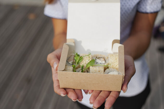 外观女孩打开一个纸板袋 里面装着一套玩具寿司 海鲜交付概念女孩午餐女士