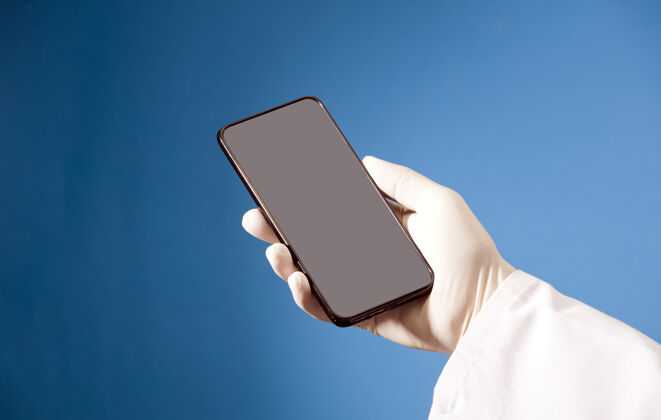 屏幕戴着卫生手套的医生手里拿着灰色屏幕的手机模型手套手机手