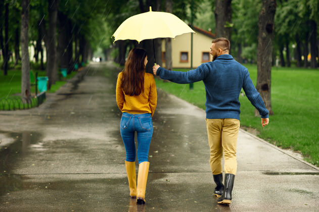 浪漫在夏季公园 背景 雨天 拥抱着伞的情侣戴曼女人在雨中的小路上悠闲地走着 小巷里的天气潮湿约会女朋友家庭