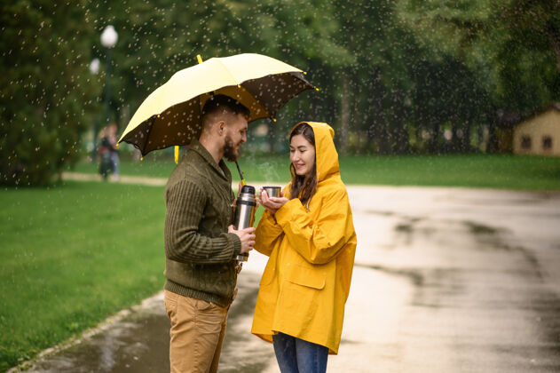 散步公园热茶情侣 夏日多雨戴曼雨中的女人站在雨伞下 漫步小径上的浪漫约会 小巷里的潮湿天气雨年轻保护