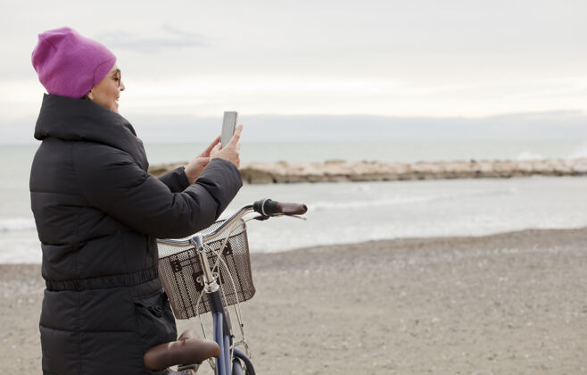 快乐优雅的女人 骑着自行车 用着自行车手机近大海 文字的空间男性海滩休闲