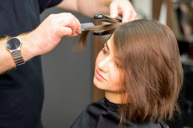 颜色一个男美发师正在美容院给年轻女子理头发长工作直