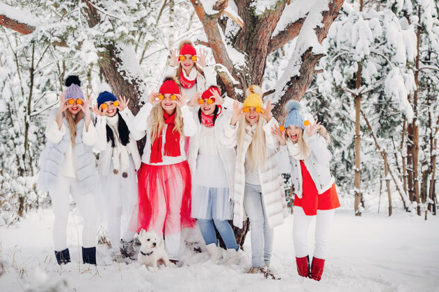 冬天冬天站着一大群带橘子的姑娘森林女孩穿着红白相间的衣服 在白雪覆盖的森林里结着水果雪新年节日