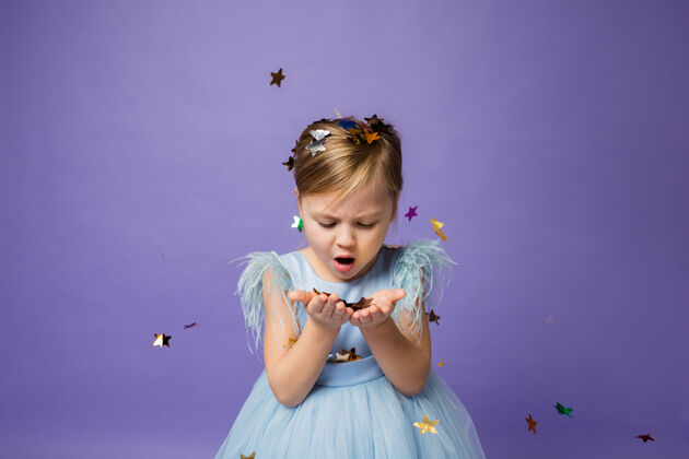 甜美小女孩用手吹紫色的纸屑呼吸宝贝小女孩