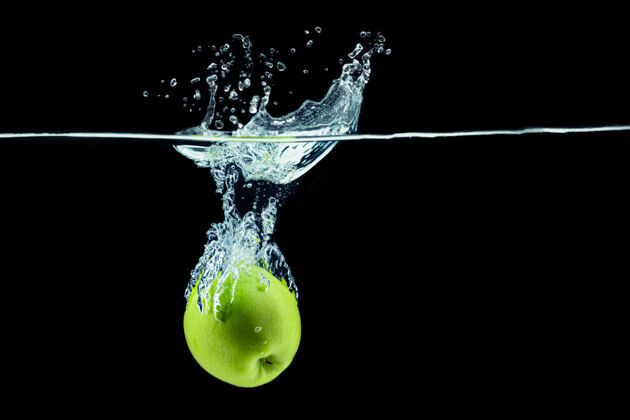 泡沫绿色的苹果掉进水里 在黑暗的背景下飞溅食物水苹果