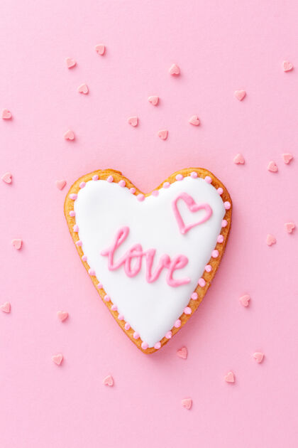食物粉色背景上印有“爱”字的心形饼干洒水形状约会