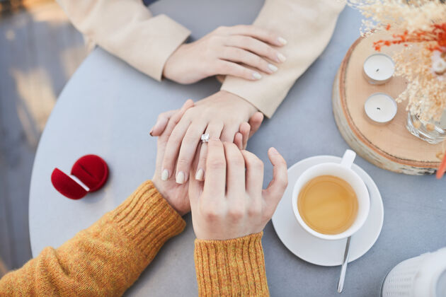 微笑在咖啡馆约会的时候 一个男人把结婚戒指戴在他女朋友的手指上饮料手优雅