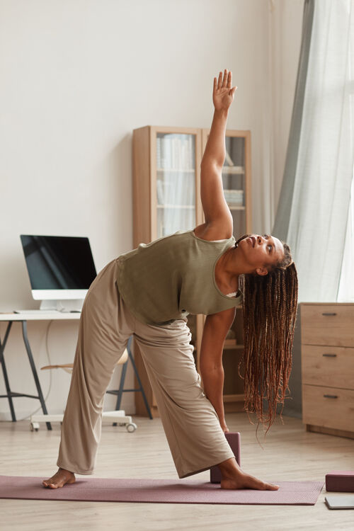 优雅非洲美女站在运动垫上 在家客厅做伸展运动家庭房间伸展瘦身