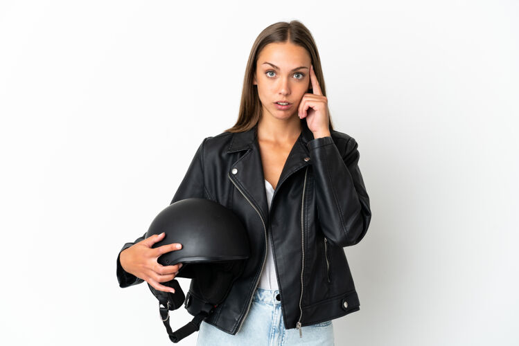 女性一个戴着摩托车头盔的女人在孤立的白色背景下思考着一个想法怀疑空白头盔