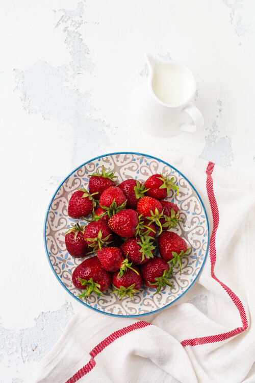 老的新鲜草莓放在白色旧混凝土表面的浅盘上使用生的甜点