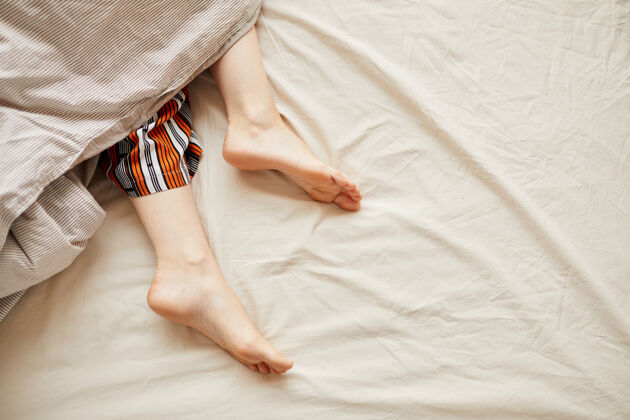 床光着脚躺在床上毯子下面的女人的特写镜头成人家庭房间度假