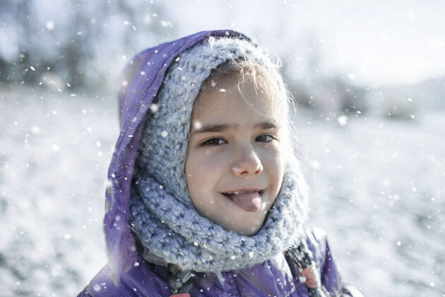 雪花戴着针织帽子的女孩 享受着冬天的第一场雪 用舌头品尝着雪味道雪雪花