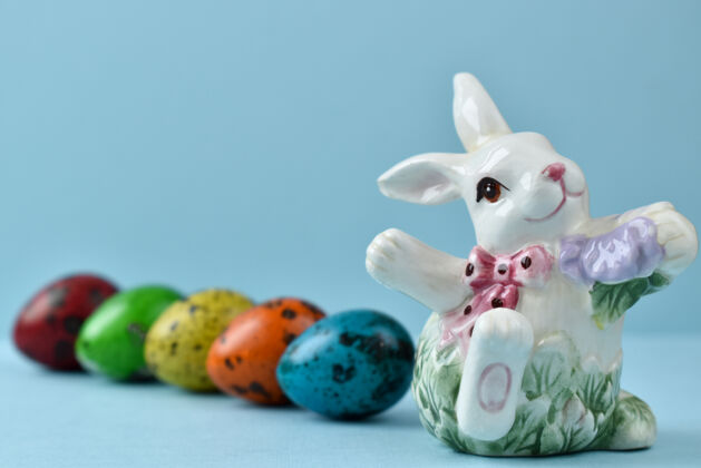 节日不同颜色的复活节鹌鹑蛋旁边放着一只兔子绘画季节传统