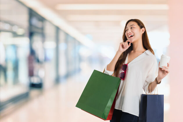 亚洲人亚洲美女博客购物和手指着购物袋在模糊的购物中心顾客购物者包