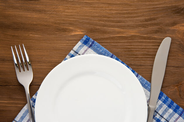 咖啡馆白色的盘子 刀叉在餐巾纸的木质背景上亚麻布餐具清洁