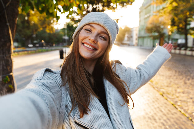女性一位穿着秋衣戴秋帽的美丽年轻女子在户外散步 自拍秋天城市看起来