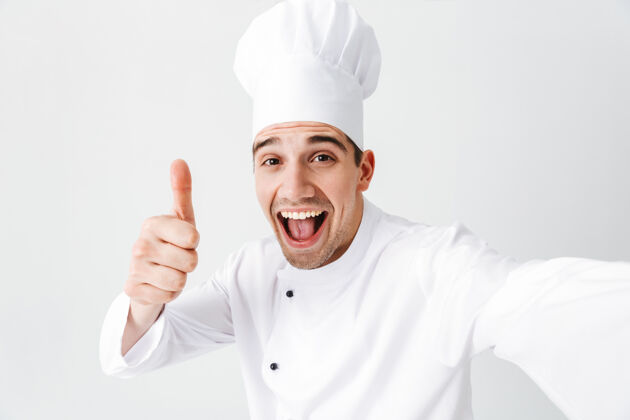 自我快乐的厨师穿着制服孤立地站在白墙上 自拍 竖起大拇指手专业年轻