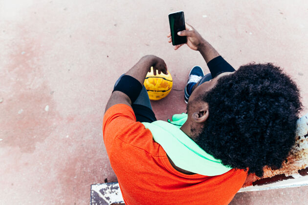 使用一个黑人男孩在篮球场上使用手机的顶视图法庭概念科技与体育电话种族非裔美国人