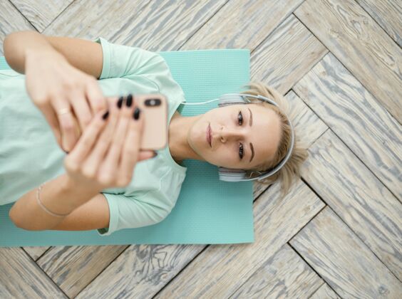运动服女性在垫子上锻炼和打电话运动耳机移动