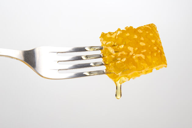 甜点几滴新鲜的蜂蜜从蜡蜜滴到桌子上叉子维生素营养和蜂产品花蜜打蜡配料