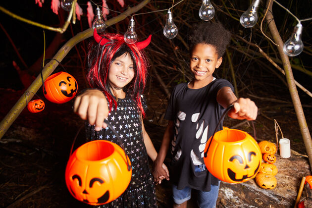 季节在万圣节派对上 两个穿着盛装的快乐的孩子抱着篮子等待款待的画像橙色装饰工艺