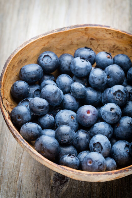 蓝莓把蓝莓放在木桌上的碗里成熟零食水果