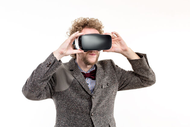 男性年轻的卷发商人穿着棕色西装使用虚拟现实耳机和体验虚拟现实隔离观看虚拟现实设备