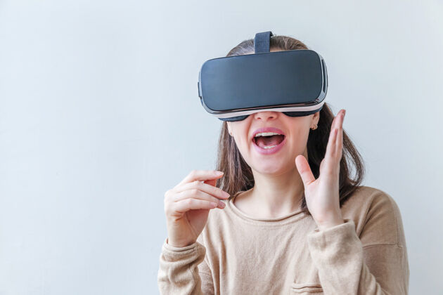 虚拟微笑的年轻女子戴着虚拟现实vr眼镜头盔耳机在白色背景上服装设备视频