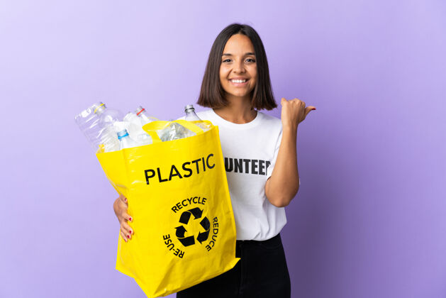 环保年轻的拉丁女子拿着一个装满废纸的回收袋 把回收隔离在紫色的指尖上 向一旁赠送一款产品责任方向手指