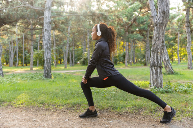 锻炼20多岁的女运动员穿着黑色运动服 在绿色公园里锻炼身体女性运动年轻