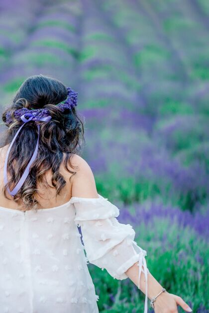 花美丽的长发和薰衣草花环在薰衣草地上的女孩手背部卷曲
