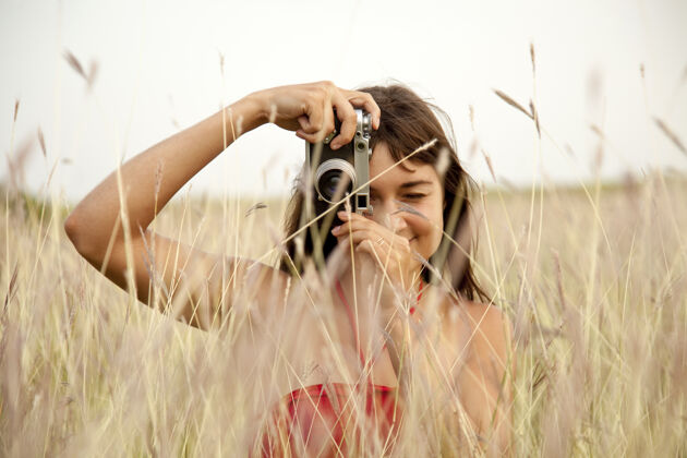 田野在草地上拿着相机的黑发女孩独自自由自然