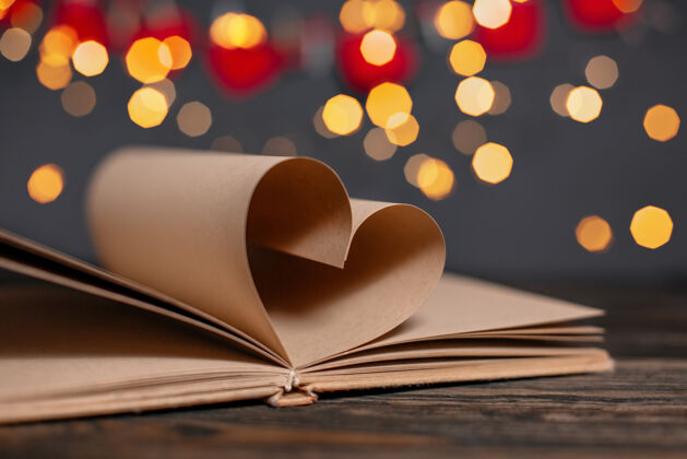 可爱心由书页做成 在灯光下 爱情和情人节的概念放在一张木桌上心教育文学
