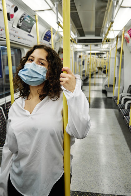 站立乘坐公共交通工具的年轻拉丁女人防护面罩旅行