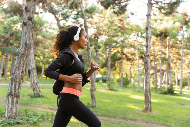 公园20多岁的美女穿着黑色运动服 一边在绿色公园里跑步一边锻炼非洲跑步黑发