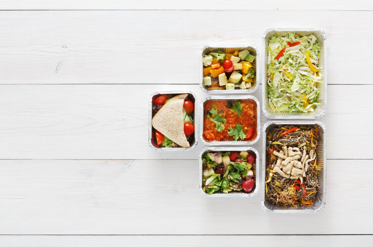 健康健康食品配送 每日定量配给铝箔盒中的食品外卖俯视图 白色木材处有复印空间早餐自然午餐