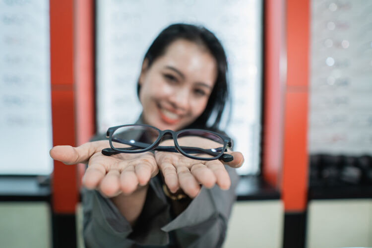 选择在一家眼科诊所 一位美女拿着眼镜在眼镜陈列柜的背景下摆姿势货架对象眼镜商