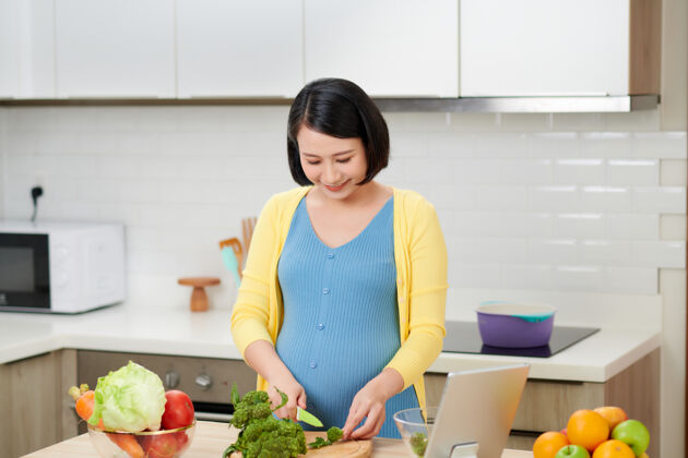 饮食孕妇切西兰花做新鲜蔬菜沙拉 女性在家准备美味的有机晚餐休闲桌子孕妇
